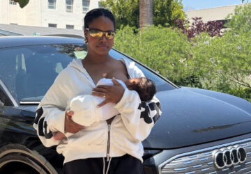Taylour Paige breastfeeding her newborn son while standing in front of an Audi E Tron after surviving a car accident.