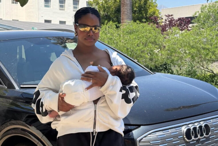 Taylour Paige breastfeeding her newborn son while standing in front of an Audi E Tron after surviving a car accident.